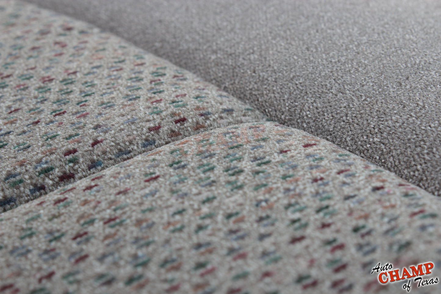 Close-up of gray seat cover fabric texture with detailed multicolor stitching.